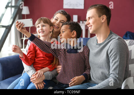 Happy couple with adopted children taking selfie at home Stock Photo