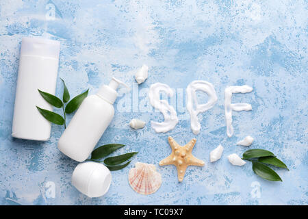 Sun protection cream and seashells on color background Stock Photo