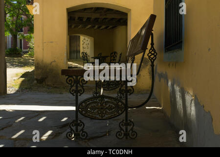 Wooden bench and wrought iron on the porch of an abandoned house, with walls painted yellow ocher Stock Photo