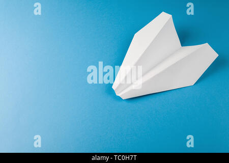 Flat lay of white paper plane on blue color background