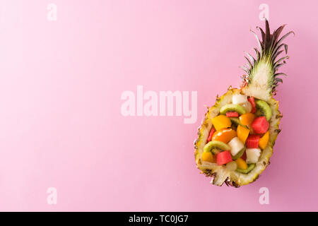 Mix fruit served inside pineapple on pink background Stock Photo