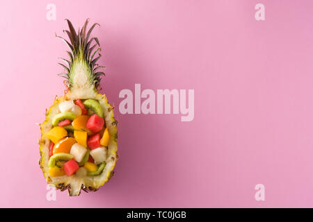 Mix fruit served inside pineapple on pink background Stock Photo