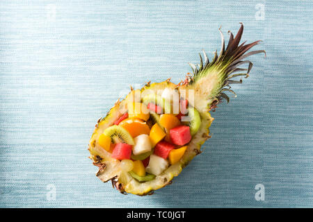 Mix fruit served inside pineapple on blue background Stock Photo