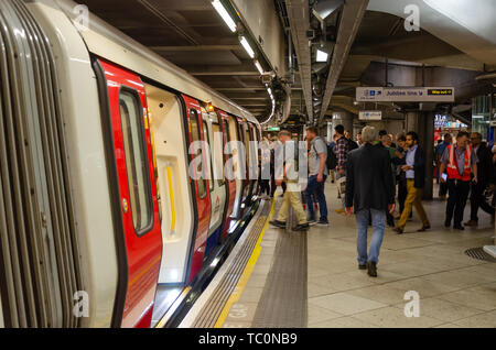 Passengers board a train at Westminster London Underground Station Stock Photo