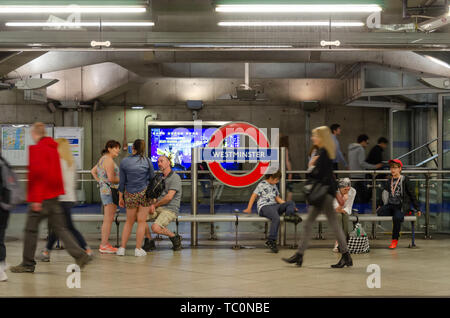 People sit on a bench on the platform at Westminster London Underground Station Stock Photo