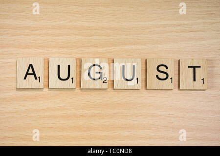 The word March, spelt out using wooden tiles on a wood effect background with scrabble numbered score values. Stock Photo