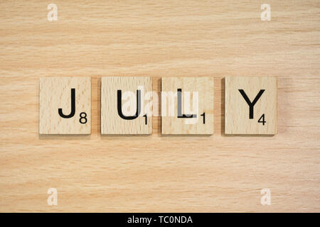 The word March, spelt out using wooden tiles on a wood effect background with scrabble numbered score values. Stock Photo