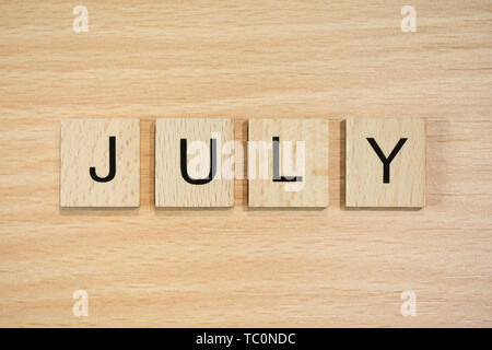 The word March, spelt out using wooden tiles on a wood effect background. Stock Photo