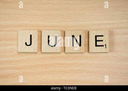 The word March, spelt out using wooden tiles on a wood effect background. Stock Photo