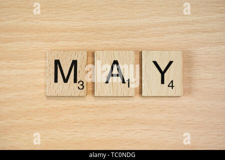 The word March, spelt out using wooden tiles on a wood effect background with scrabble numbered score values. Stock Photo