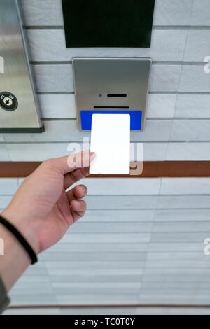 securing lift or elevator access control, man's hand is holding a key card lay up to insert in card hold for unlocking elevator doors before up or dow Stock Photo