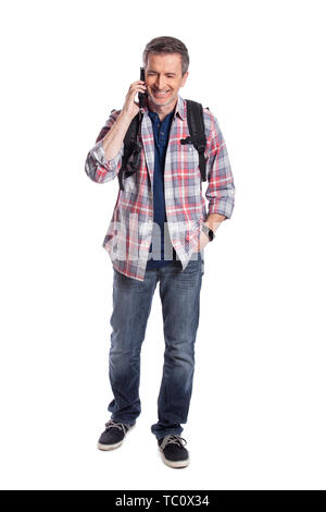 Male tourist or a hiker using a cellphone to call or message a rideshare so he can travel.  The man is wearing a backpack and using a smart phone.  Is Stock Photo