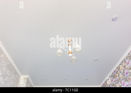 Stretch matte ceiling in the room with a chandelier and spotlights, with natural light Stock Photo