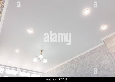Stretch ceiling in the room with a chandelier and spotlights Stock Photo