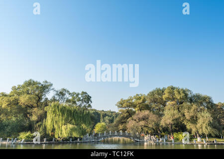 Autumn China Fushun early morning park river bank willow stone bridge cruise ship Stock Photo