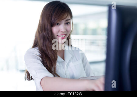 Beautiful asian student finger click screen and check book data Stock Photo