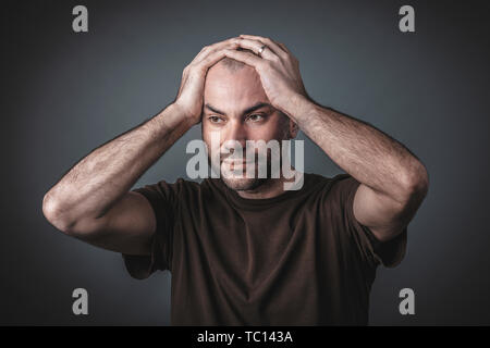 Studio portrait of pensive man with his hands holding his head. Casual clothes. Stock Photo