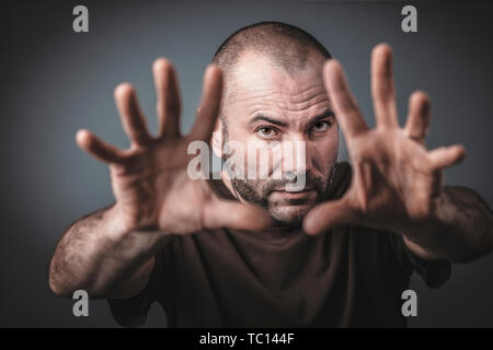 Studio portrait of Caucasian man with open hands and arms outstretched forward. Selective focus on the face. Stock Photo