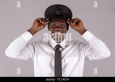 England UK. May 2019. Portrait of a male chauffeur adjusting his black uniform hat. Stock Photo