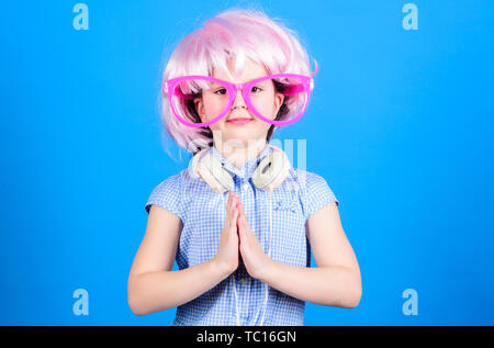 Keep calm and partying. Small child with DJ headphones. Little girl using wireless headset for DJ disco. Adorable DJ girl wearing fancy wig and glasses. Enjoying music playing on DJ party. Stock Photo