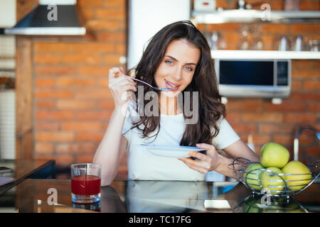 Happy young woman eating pumpkin soup in kitchen Stock Photo