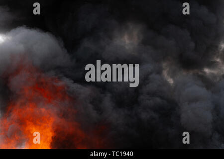 Flames of strong red fire and motion blur black clouds smoke covered ...