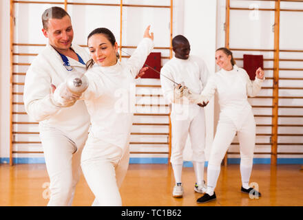 Female fencer practicing  movements with trainer at fencing workout Stock Photo