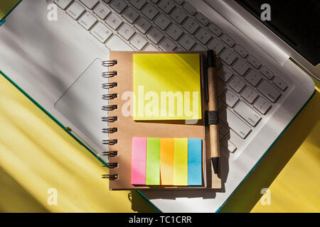 Top view of Spiral Notebook with Pen in Holder with colorful sticky page markers- Workspace with laptop Stock Photo