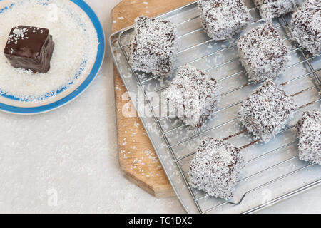 Homemade lamington cakes. Australian cake. Sponge cake cut into cubes coated in an outer layer of chocolate sauce and rolled in desiccated coconut Stock Photo