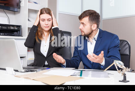 Frustrated female and male sales managers working in showroom, looking at laptop monitor Stock Photo