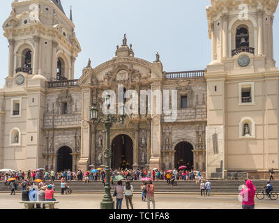 Lima, Peru - March 29, 2018: People with colorful umbrellas on a hot day on the street of Lima next to Parroquia del Sagrario. Easter time. Good Frida Stock Photo