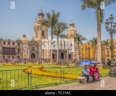 Lima, Peru - March 29, 2018: People with colorful umbrellas on a hot day on the street of Lima next to Parroquia del Sagrario. Easter time. Good Frida Stock Photo