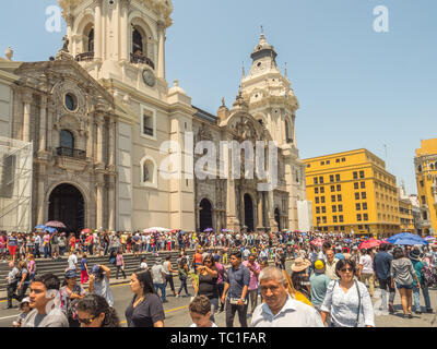 Lima, Peru - March 29, 2018: People with colorful umbrellas on a hot day on the street of Lima next to Parroquia del Sagrario. Easter time. Good Frida Stock Photo