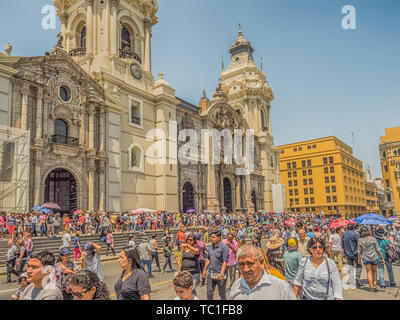 Lima, Peru - March 29, 2018: People with colorful umbrellas on a hot day on the street of Lima next to Parroquia del Sagrario. Easter time. Good Frida Stock Photo