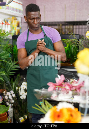 Portrait of pensive African American man florist thinking over creating of flower arrangement in shop Stock Photo