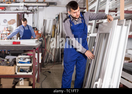Laborer is inspecting the window frame in workshop. Stock Photo