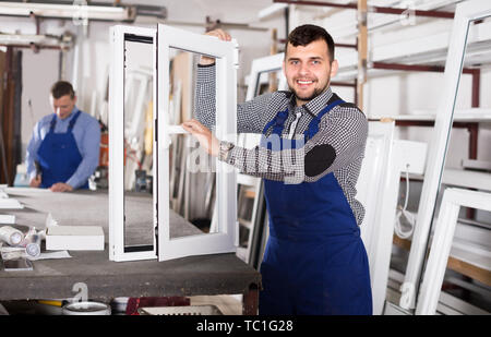 Workman is demonstrating the window frame in workshop. Stock Photo