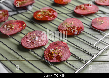 Cooling rack with tasty raw beet chips on wooden table Stock Photo