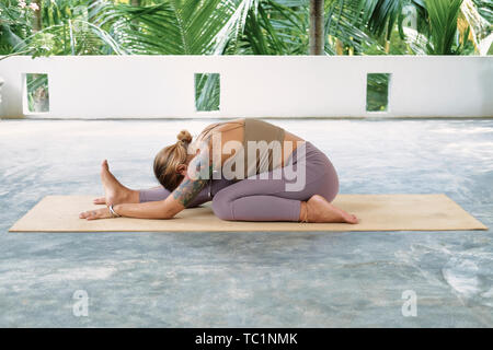 Woman Practicing Advanced Yoga on Organic Mat. Series of Yoga Poses. Tropical background. lifestyle Concept Stock Photo