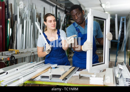 Two masters are working with window frame in the window workshop. Stock Photo