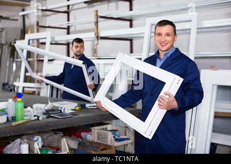 Two  positive careful workmen inspecting PVC manufacturing output in workshop Stock Photo