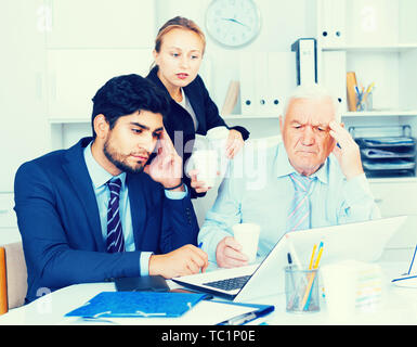 Old man is having complicated issue with reports made by subordinates in office. Stock Photo