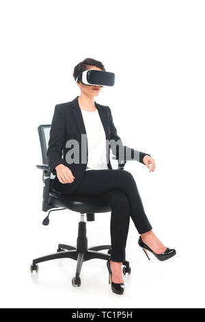 mixed race businesswoman using virtual reality headset while sitting in office chair on white background Stock Photo