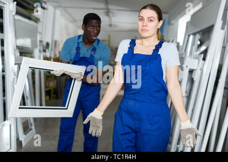 Two masters are conflicting in time working with window frame in the window workshop. Stock Photo