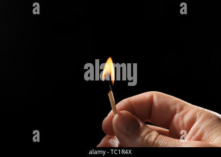 Male hand with burning match on dark background Stock Photo