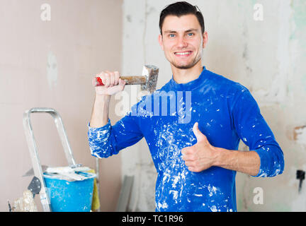 Smiling male builder showing thumb up with hammer in hand Stock Photo