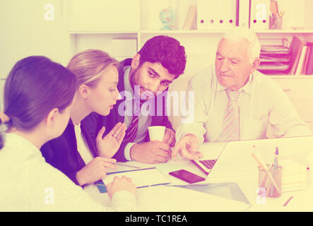 Managers are writing financial reports and discussing with mature boss in the office. Stock Photo