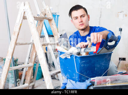 Professionality worker repairing room and looking for necessary tool in toolbox Stock Photo