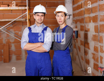 Portrait of two confident workers in uniform inside brick cottage Stock Photo
