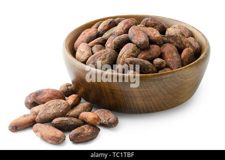 Unpeeled cocoa beans in a brown wooden bowl next to a pile of unpeeled cocoa beans isolated on white. Stock Photo